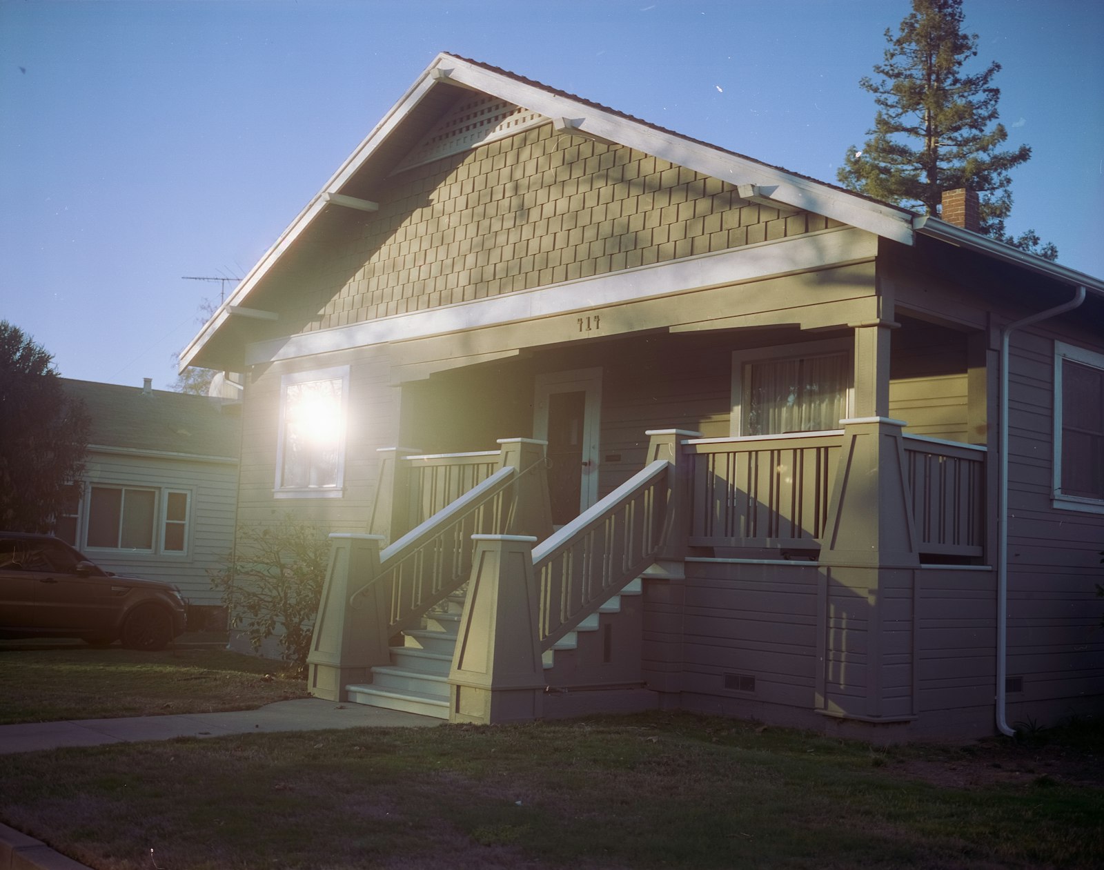 White wooden house with a front porch near green trees, a home scene for buyers moving to Campbell CA